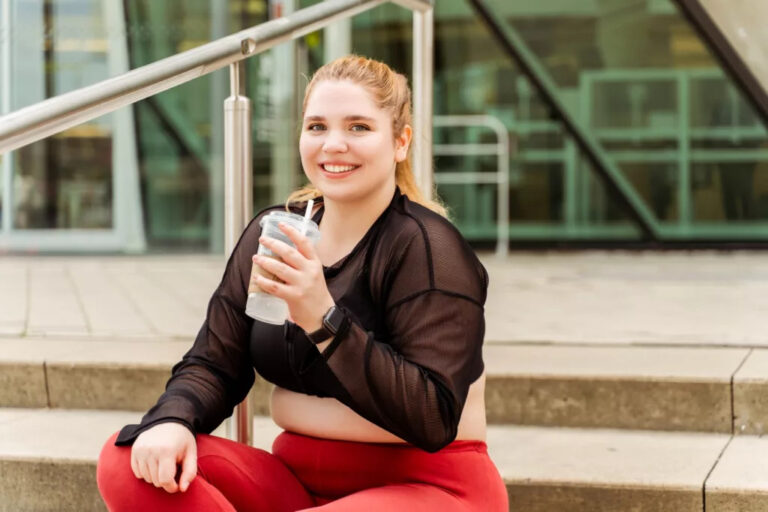 happy plus size woman in sportswear sitting on the steps and drinking water body positive plus size 1024x682 1 768x512